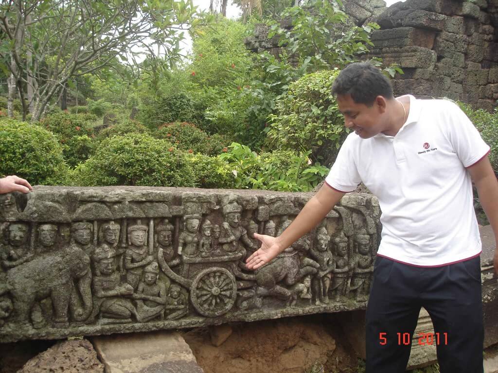 Guide explaining story on carved panel, Ta Prohm Temple, Takeo