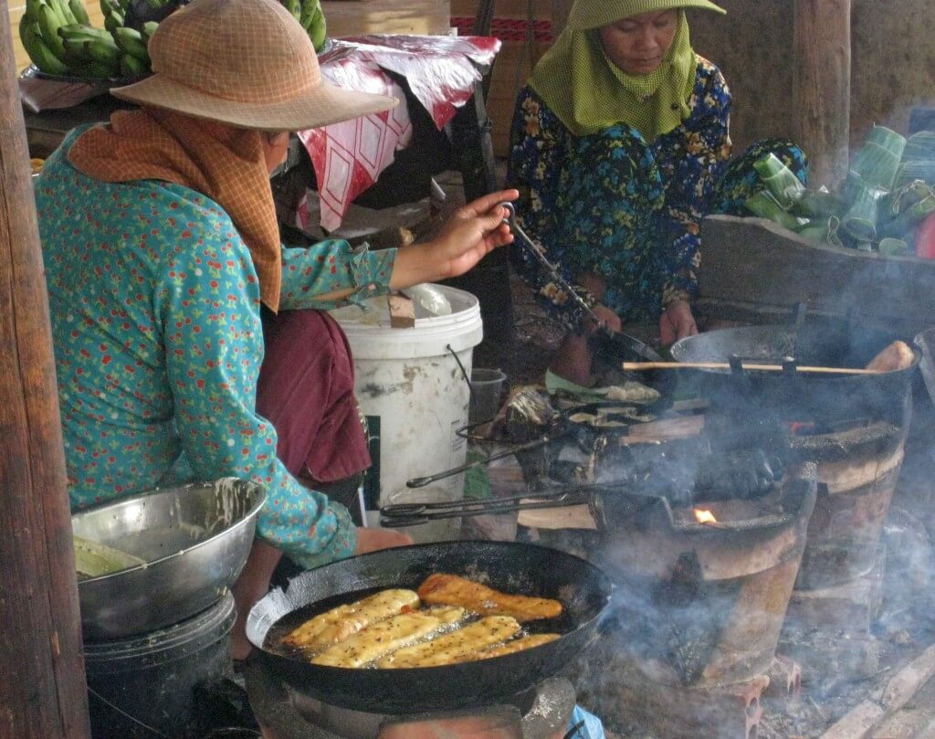 Women of Kep cooking fish at seafood market, beachside