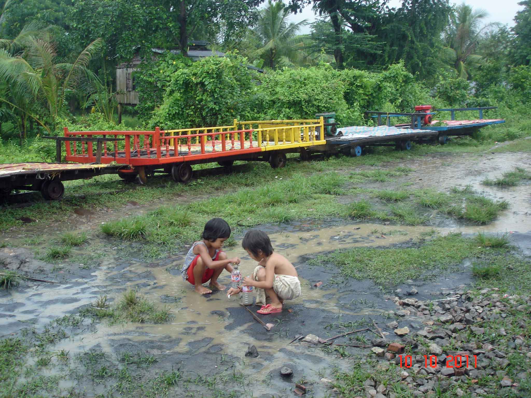 Children playing in the puddles beside Bamboo Train (Norry)